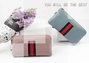 Detail view of leather zip-around wallets in blue and pink with striped webbing