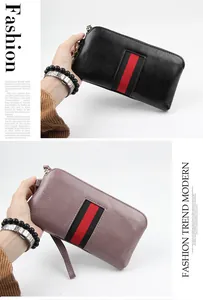 Detail of leather wallets in black and purple featuring striped webbing and gold zippers