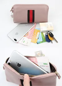 Detail of pink pebbled leather long wallet with green and red striped webbing trim
