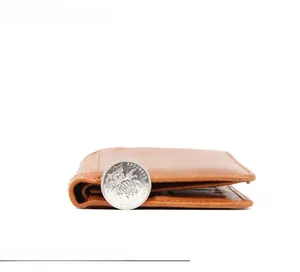Slim profile view of a brown leather wallet showing thickness compared to a coin
