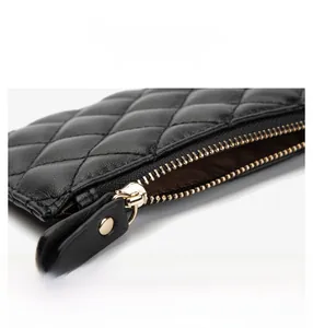 Detail view of exquisite gold metal zipper on black quilted sheepskin leather pouch