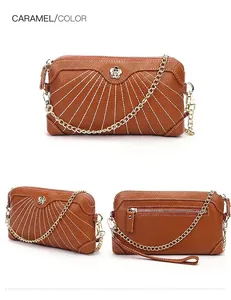 Λεπτομέρεια δερμάτινης τσάντας clutch σε καραμελέ χρώμα με λευκές ραφές και μεταλλικό άνθος