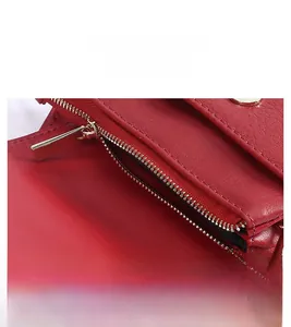 Close-up of golden metal zipper on red pebble grain leather crossbody phone bag