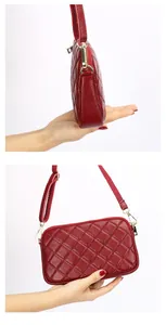 Close-up of red genuine leather crossbody bag with quilted rhombic pattern and gold zipper