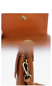 Detail of vintage gold magnetic closure and hardware on brown lychee grain leather bag