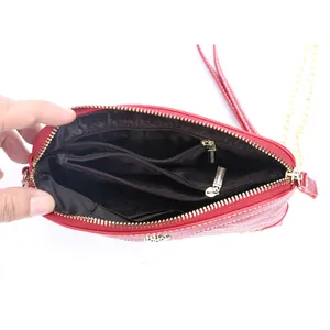 Red leather crossbody bag with white stitching, gold chain, and multi-compartment interior