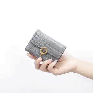 Detalle de tarjetero en piel gris con grabado de cocodrilo y cierre dorado