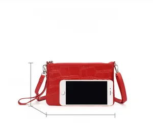 Rote Clutch mit Krokodilmuster aus Leder und Maßen von 23,5 cm Länge und 1 cm Dicke