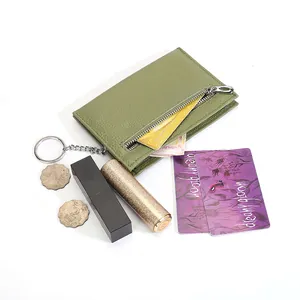 Grass green genuine leather coin purse with keychain chain, coins and lipsticks on white background