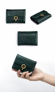 Detalle de tarjetero en piel con relieve de cocodrilo verde oscuro y hebilla dorada