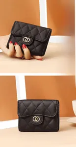 Detailed view of black quilted leather wallet with gold metal logo and flap closure