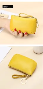 Primer plano de billetera de cuero amarillo con grano, cremallera dorada y correa