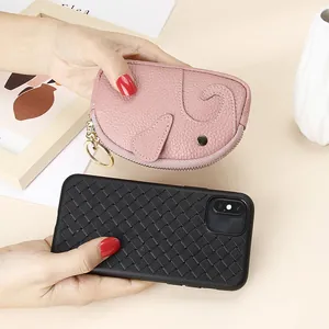Pink leather elephant coin purse with gold keychain alongside woven black phone case