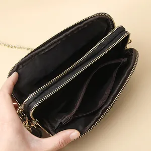 Black genuine leather crossbody phone bag with triple zip compartments and gold chain strap