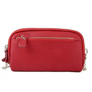 Minimalist red pebble leather crossbody bag with three zippers and gold chain strap