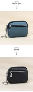 Close-up of dual-zipper leather coin pouches in denim blue and black with keychains