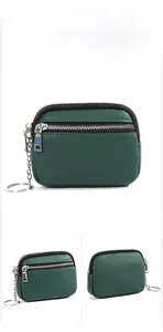 Macro view of dark green pebbled leather coin purse with double zippers and key ring