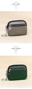 Close-up of dual zipper leather coin purses in light gray and dark green with keychains