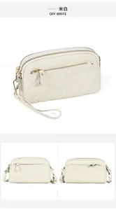 Detail view of beige quilted leather crossbody bag with multiple zipper compartments