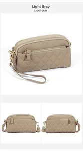 Detail view of light gray lychee leather bag with quilted pattern and gold zippers