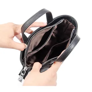 Vista interna del bolso de cuero negro con dos compartimentos y un bolsillo central con cremallera
