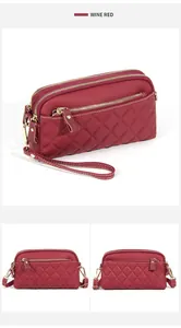 Close-up of wine red quilted leather handbag showing multi-zipper compartments and texture