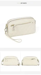 Detailed macro view of off-white quilted leather handbag with triple zipper and gold hardware