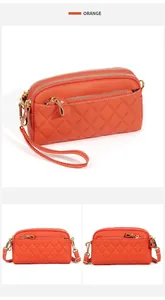 Detail of orange quilted leather crossbody bag with three zipper compartments and gold hardware