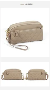 Detail of light gray quilted leather crossbody bag with triple zipper and lychee texture