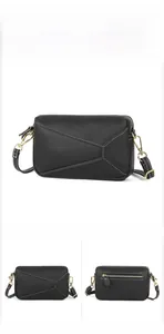 Detail view of black pebble leather crossbody bag with geometric puzzle stitching and strap