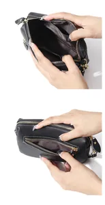 Detail view of black pebble leather crossbody bag with white stitching and multi-compartment zip