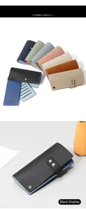 Détail d'un porte-cartes en cuir grainé avec plusieurs fentes et fermeture à boucle en métal