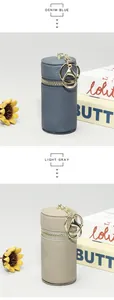 Détail de mini pochettes cylindriques en cuir bleu denim et gris clair avec porte-clés