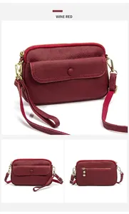Detail view of wine red lychee grain leather crossbody bag showing multiple zip pockets