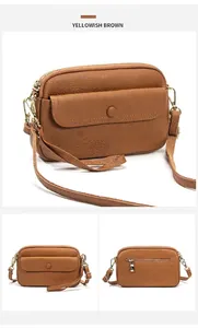Detailed view of yellowish brown leather crossbody bag with pebble texture and gold zippers