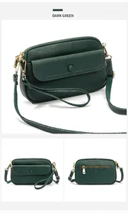 Detail view of dark green pebbled leather crossbody bag with adjustable straps
