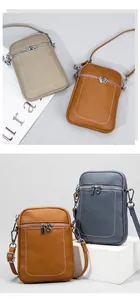 Detail of lychee pattern leather phone bags in khaki, brown, and blue with silver zippers