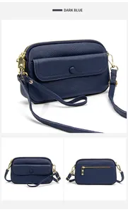 Detail view of dark blue litchi grain leather crossbody bag with golden hardware