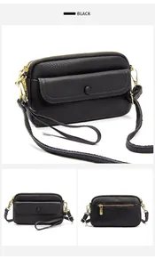 Detail of black lychee grain leather handbag with gold hardware and multi-zipper compartments