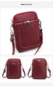Detail view of wine red pebbled leather phone bag with silver zippers and stitching