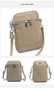 Detail view of light gray pebbled leather crossbody phone bag with headphone port and zippers