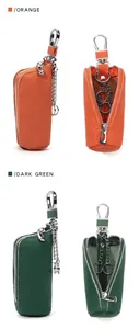 Detail of leather car key cases in orange and dark green with zipper and metal hook