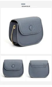 Detail van denim blauwe leren mini-tas met gouden ketting en lychee korreltextuur