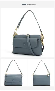 Detail view of denim blue pebbled leather crossbody bag with light gold hardware