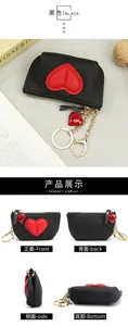 Detail view of black pebbled leather mini wallet with red heart patch and gold keychain