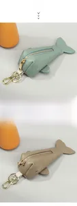 Detail of whale-shaped cowhide key pouches in light blue and gray with gold zippers