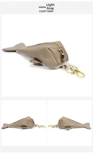 Macro shot of light gray grain leather fish-shaped key pouch with gold metal zipper and hardware