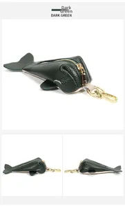 Detailed macro view of dark green fish-shaped leather coin purse with golden hardware