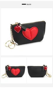 Detail view of black pebble leather mini wallet with red heart patch and gold keychain