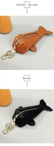 Detailed close-up of fish-shaped leather key pouches in earthy yellow and black with gold zippers